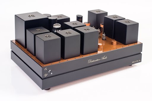 High-end tube amplifier with multiple black transformer covers and a wooden base, featuring The Phono Stage branding and visible tubes. High-end tube amplifier with multiple black transformer covers and a wooden base, featuring The Phono Stage branding and visible tubes.