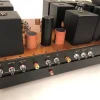 A row of vintage audio equipment including a mixer with multiple knobs and switches, and The Phono Stage, set on a wooden tabletop. A row of vintage audio equipment including a mixer with multiple knobs and switches, and The Phono Stage, set on a wooden tabletop.