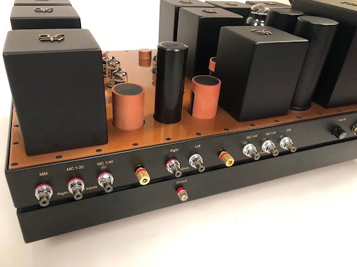 A row of vintage audio equipment including a mixer with multiple knobs and switches, and The Phono Stage, set on a wooden tabletop.