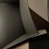 Close-up of a Vista 3-Way Horn Speakers with a sleek, curved metallic back and a wooden armrest, inspired by audiophile design aesthetics. Close-up of a Vista 3-Way Horn Speakers with a sleek, curved metallic back and a wooden armrest, inspired by audiophile design aesthetics.
