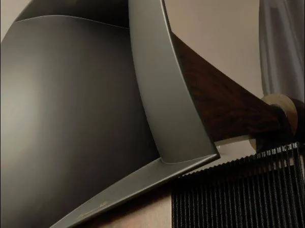 Close-up of a Vista 3-Way Horn Speakers with a sleek, curved metallic back and a wooden armrest, inspired by audiophile design aesthetics. Close-up of a Vista 3-Way Horn Speakers with a sleek, curved metallic back and a wooden armrest, inspired by audiophile design aesthetics.