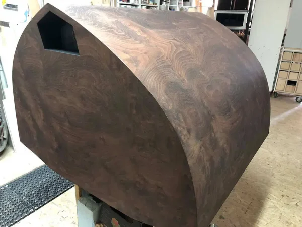 A large, geometric wooden Vista 3-Way Horn Speakers with a dark, swirling grain pattern and a pentagonal opening, displayed indoors. A large, geometric wooden Vista 3-Way Horn Speakers with a dark, swirling grain pattern and a pentagonal opening, displayed indoors.