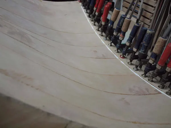 Curved plywood sheets in a workshop with an array of clamps and Vista 3-Way Horn Speakers lined up on the side. Curved plywood sheets in a workshop with an array of clamps and Vista 3-Way Horn Speakers lined up on the side.